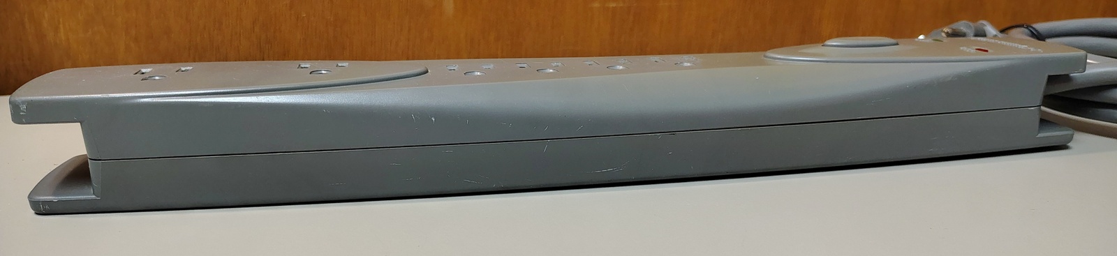 Side profile showing the elongated tapered enclosure, integrated cord-management guides, and push-button power switch.