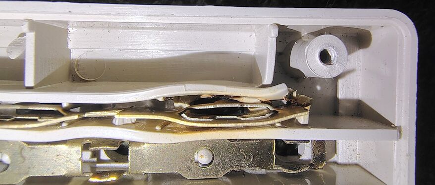 Close-up of the heat-damaged receptacle contact assembly showing melted plastic and deformation surrounding the outlet contact structure.