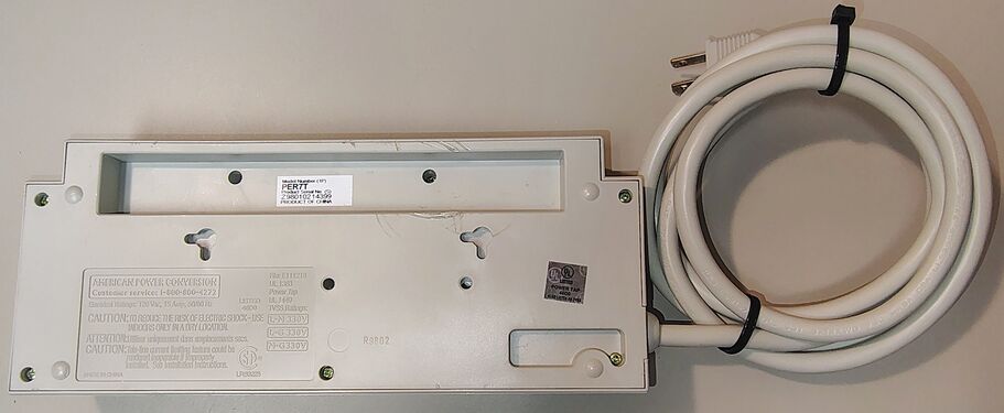 Underside overview showing molded regulatory information, mounting provisions, serial-number label, and attached power cord.
