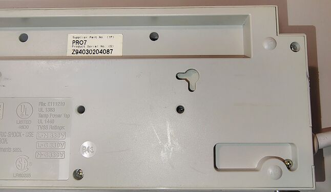 Cord-entry side of the underside showing mounting features, enclosure hardware, and molded markings.