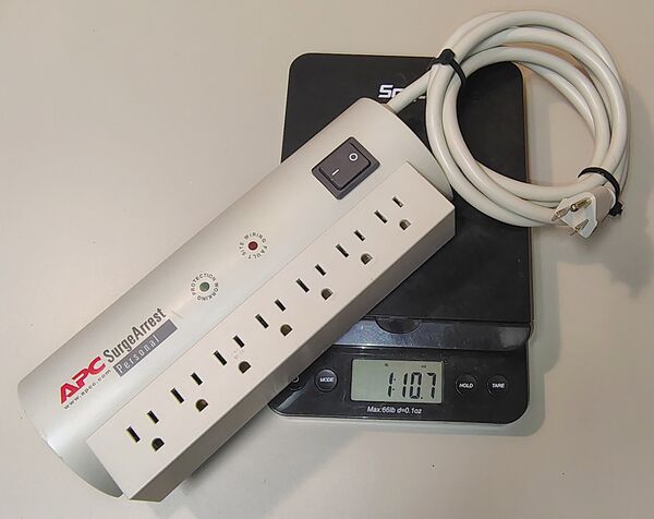 APC SurgeArrest Personal PER7T on a digital scale showing a weight of approximately 1 lb 10.7 oz (757 g).