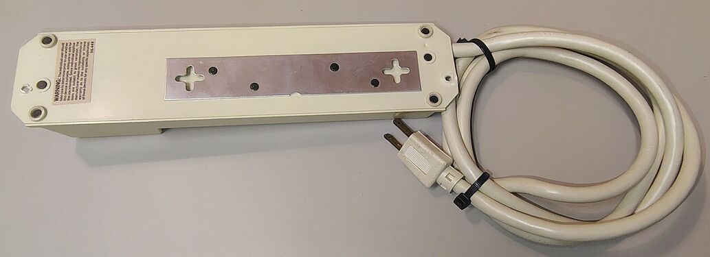 Underside view showing the metal mounting plate, keyhole slots, and attached power cord.
