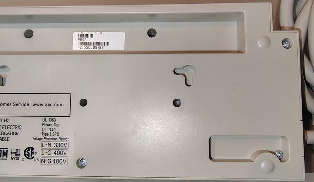 Cord-entry area showing wall-mounting features, serial-number label, and regulatory-information label.
