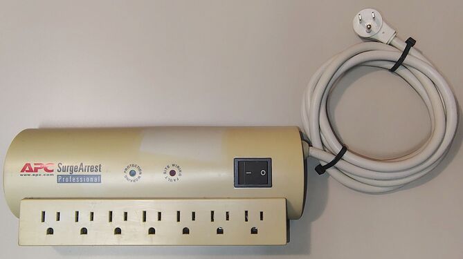 Overall view of the documented APC SurgeArrest Professional PRO7 showing substantial enclosure yellowing, attached six-foot power cord, and right-angle grounding attachment plug.