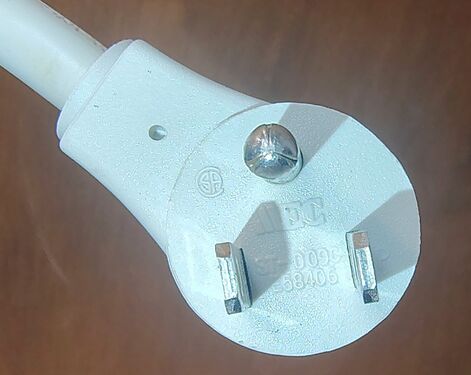 Close-up of the right-angle grounding attachment plug showing molded certification markings and construction details.