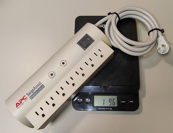 APC SurgeArrest Professional PRO7 on a digital scale showing a weight of approximately 1 lb 9.6 oz (726 g).