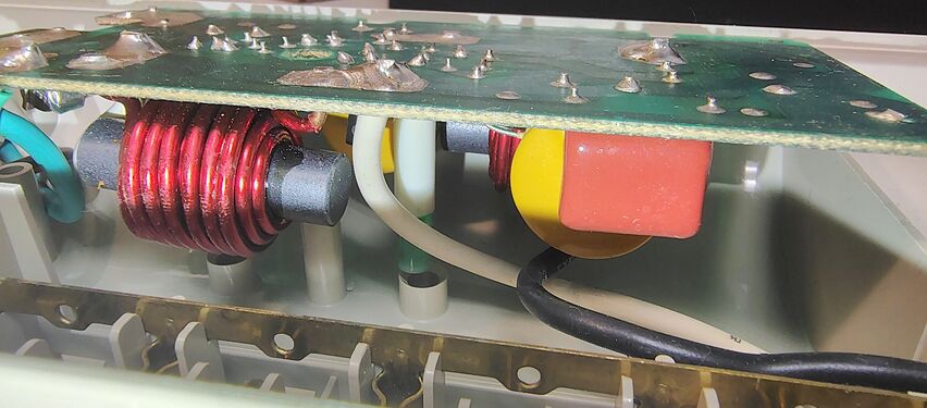 Low-angle view of the ©1993 suppression board showing filtering inductors, suppression components, wiring, and outlet-contact strips.