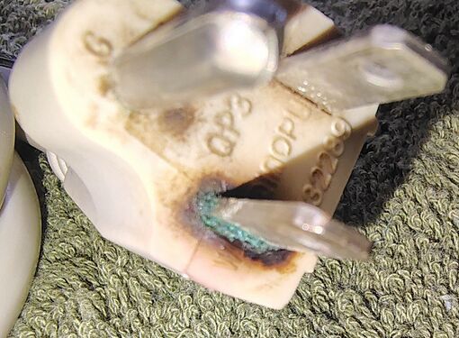 Close-up of severe heat discoloration and oxidation around the plug blade.