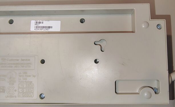 Cord-entry end underside detail showing mounting provisions, enclosure markings, and serial-number recess.