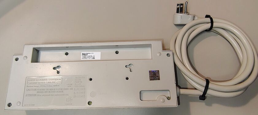 Underside view showing labels, mounting slots, cord routing, and attached power cord.