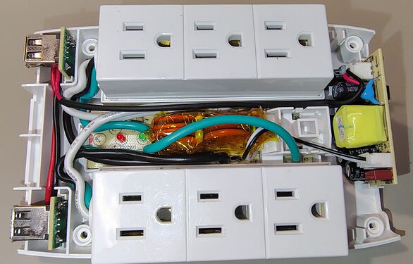 Internal construction showing rotating outlet assemblies, surge-suppression circuitry, USB charging circuitry, and internal wiring.