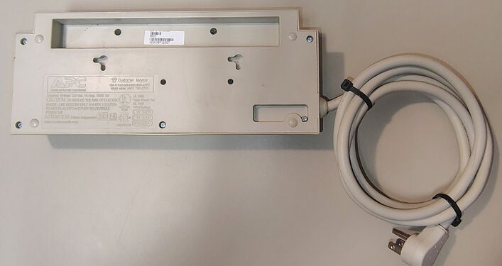 Underside view showing labels, mounting slots, power-cord entry, and attached power cord.