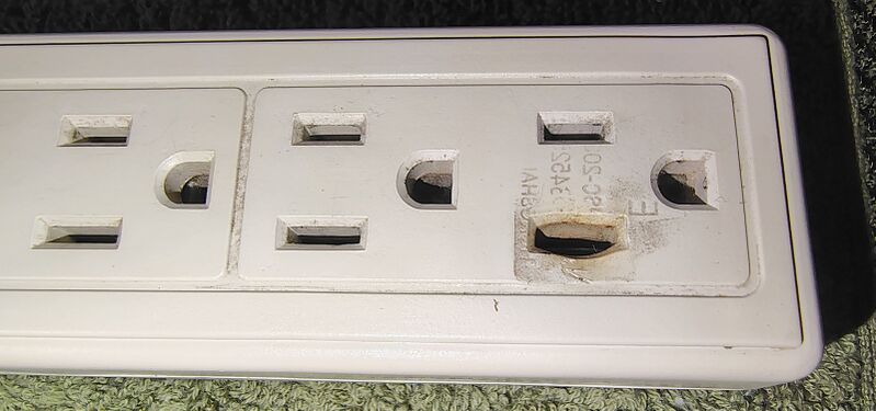 Heat-damaged outlet with melted plastic.
