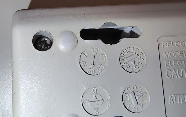 Conventional Phillips-head enclosure screw adjacent to the molded date-code wheels.