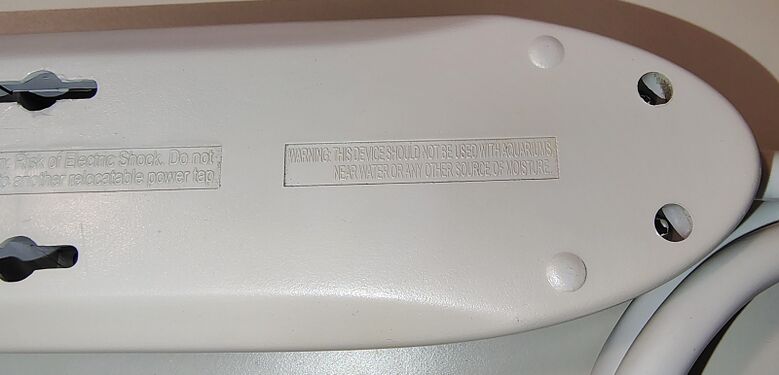 Cord-entry end underside detail showing enclosure hardware and safety markings.