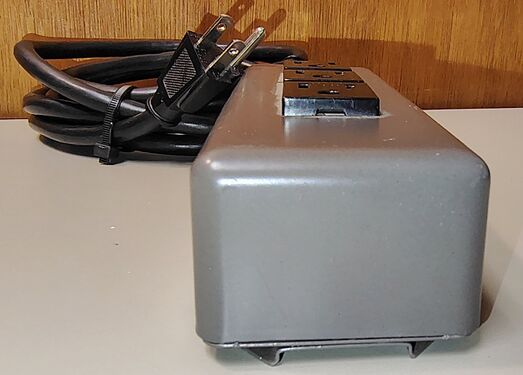Cord-entry end showing the integrated 15-amp resettable circuit breaker and power-cord strain relief.