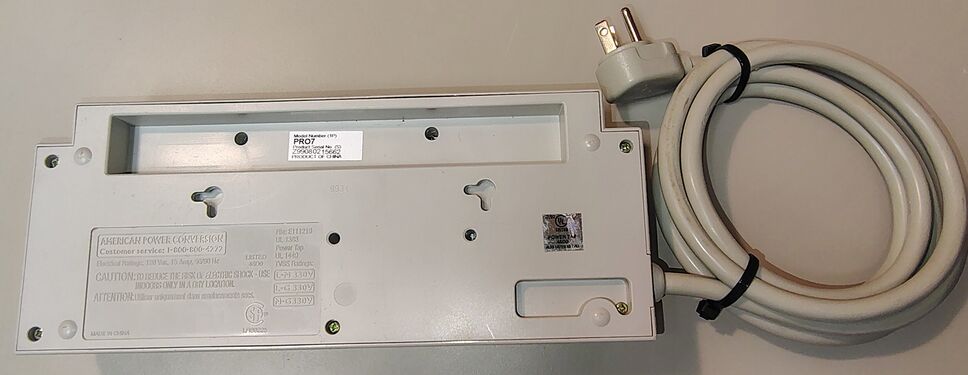 Underside showing product markings, mounting slots, serial-number label, and attached power cord.