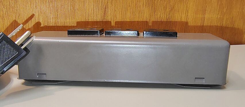 Side profile of the enclosure showing the low-profile steel construction and elevated outlet modules.